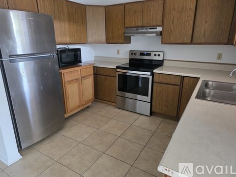 A kitchen with a stainless steel refrigerator, microwave, oven, and sink.