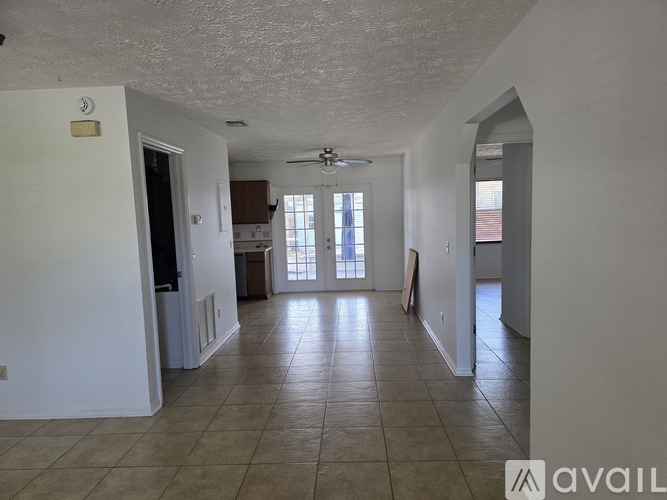 A spacious room with tiled flooring and a ceiling fan.