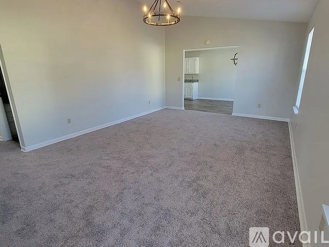 A spacious room with a carpeted floor and a chandelier hanging from the ceiling.