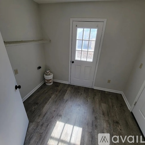 A room with a white door and a window with a view of a building.