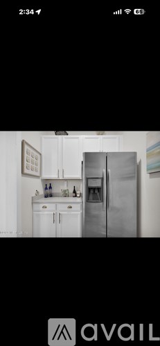 A kitchen with white cabinets and a stainless steel refrigerator.