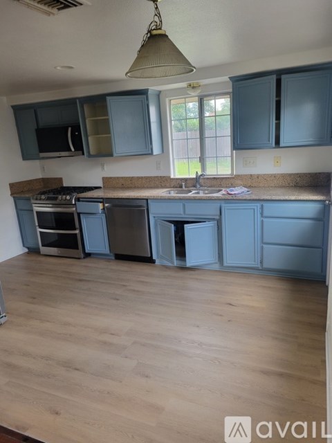 A kitchen with blue cabinets and a wooden floor.