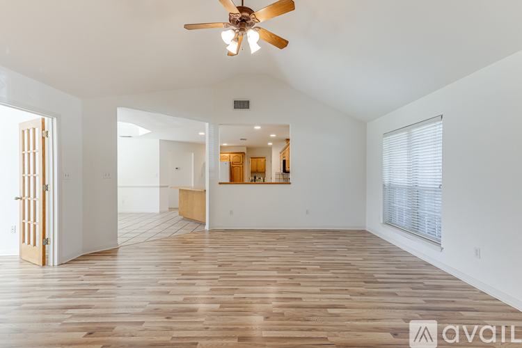 A spacious room with wooden floors and a ceiling fan.