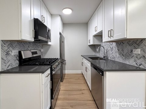 A modern kitchen with white cabinets and black countertops.