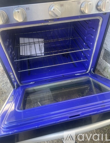 A blue oven with the door open showing the interior.