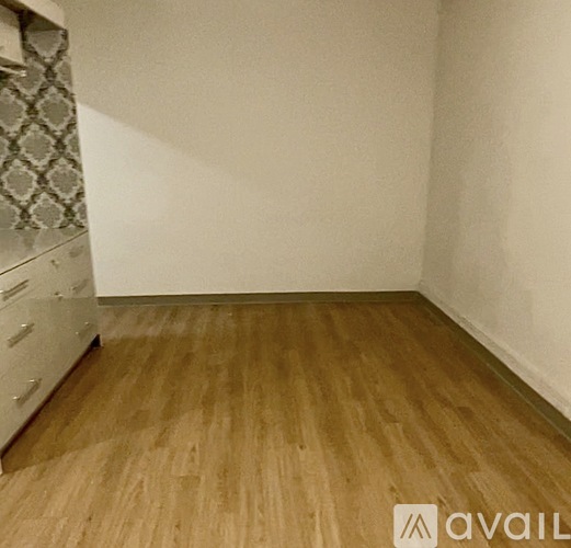 A room with wooden flooring and a white wall.