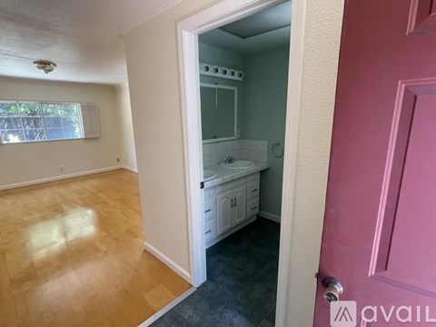 A kitchen with white cabinets and a pink door.