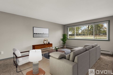 A living room with a grey couch, a chair, a lamp, and a painting on the wall.