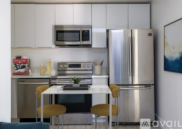 A modern kitchen with stainless steel appliances and a dining table with chairs.