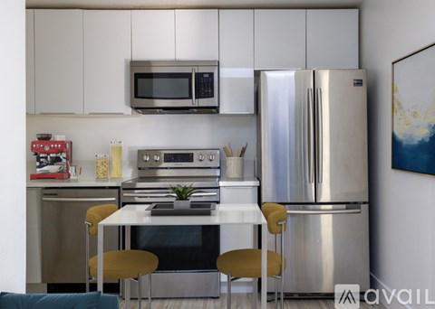 A modern kitchen with stainless steel appliances and a dining table with chairs.