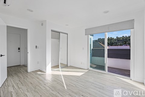 A spacious room with white walls and a wooden floor.
