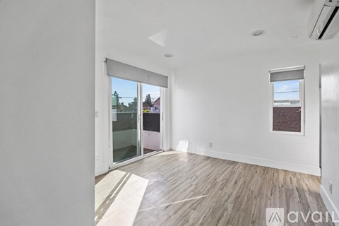 A room with wooden flooring and a window overlooking a building.