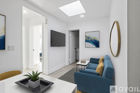 A living room with a blue couch and a flat screen TV mounted on the wall.