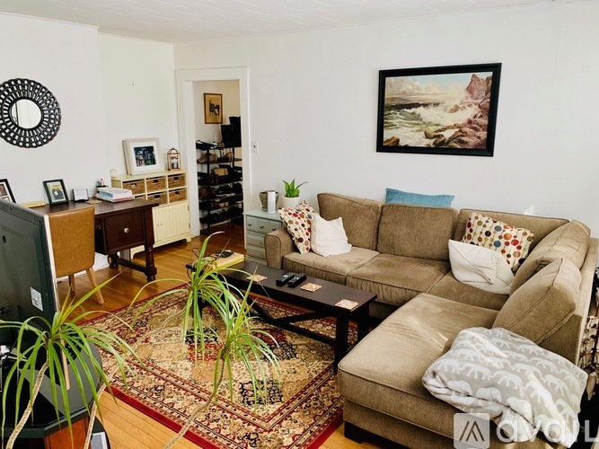 A living room with a couch, a rug, and a painting on the wall.