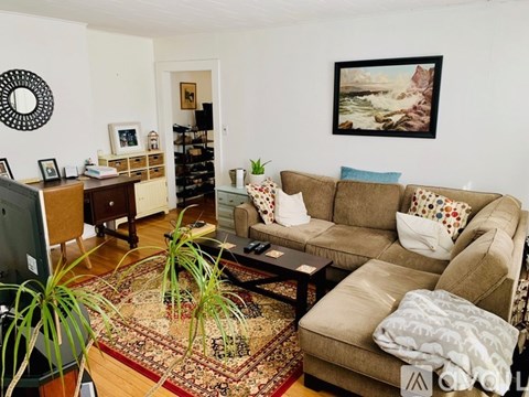 A living room with a couch, a rug, and a painting on the wall.