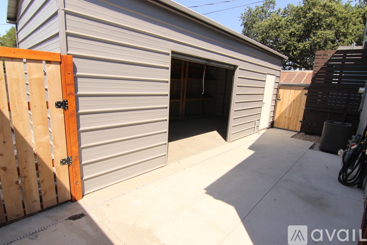 A grey building with a wooden door and a brown fence.
