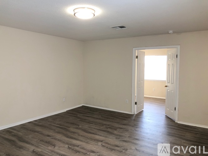 A room with wooden flooring and a doorway leading to another room.