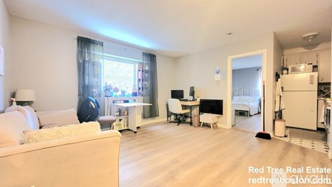 A living room with a white couch and a kitchen area in the background.