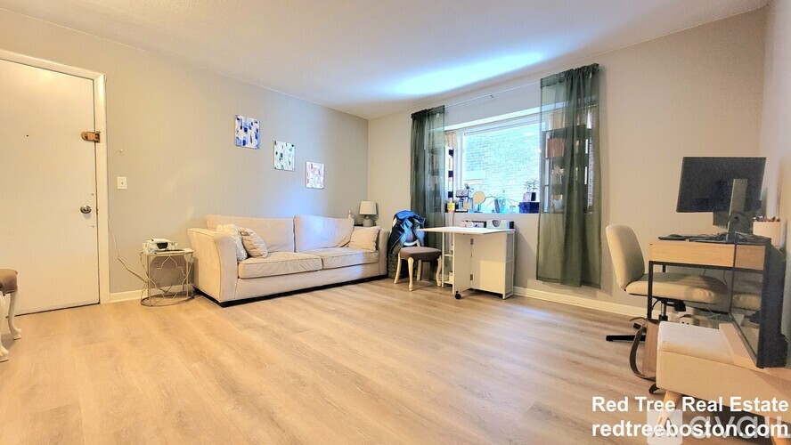 A living room with a white couch, a desk with a computer, and a television on a stand.