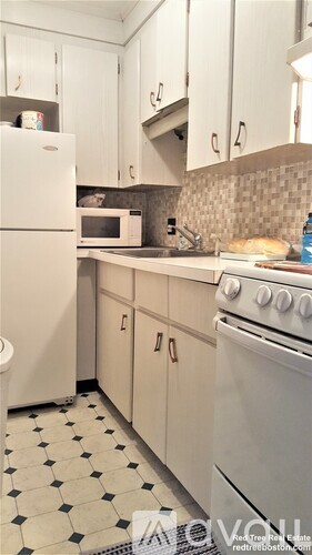 A white fridge and oven in a kitchen with black and white tiles.
