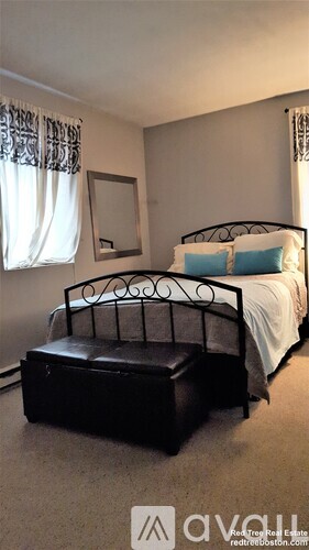 A bedroom with a black metal bed frame and a bench.