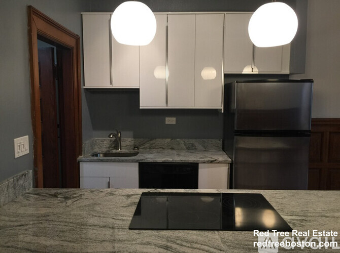 A kitchen with a sink, cabinets, and a refrigerator.