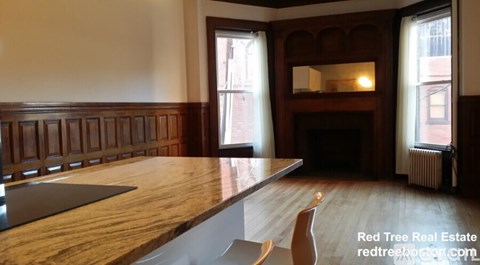 A wooden table with a bench in front of a fireplace in a room with a window.