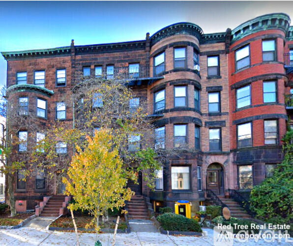A large red brick building with a tree in front of it.