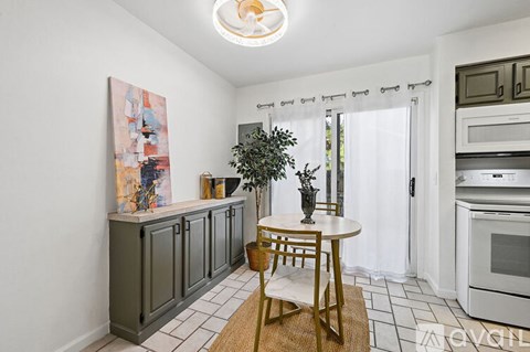 A kitchen with a table and chairs and a painting on the wall.