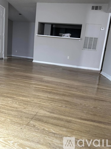 A room with wooden flooring and a window with blinds.