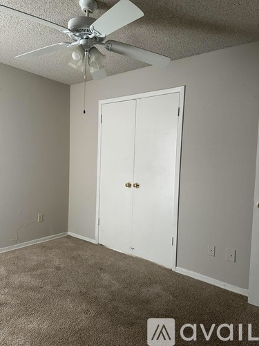 A room with a white door and a ceiling fan.