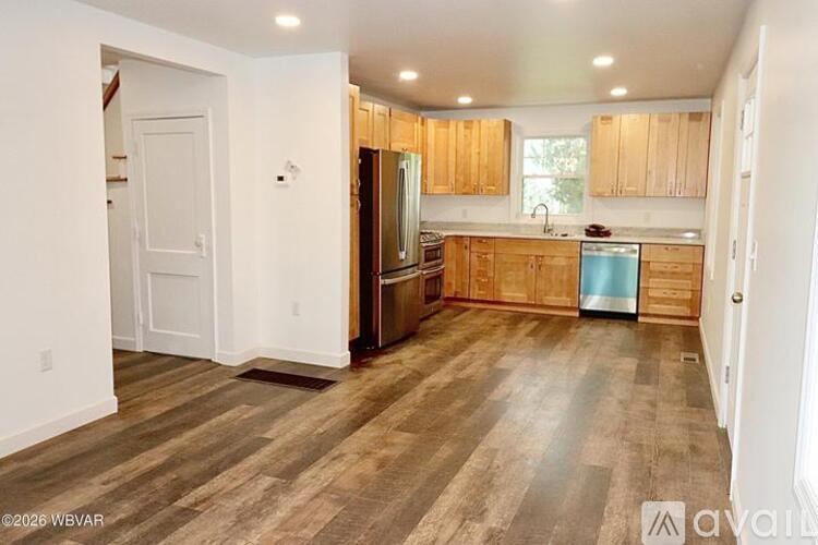 A kitchen with wooden floors and cabinets.