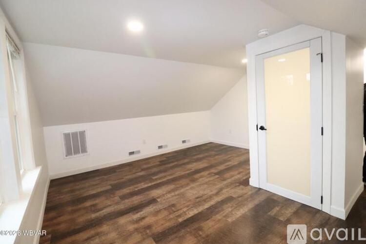 A room with wooden flooring and a white door.
