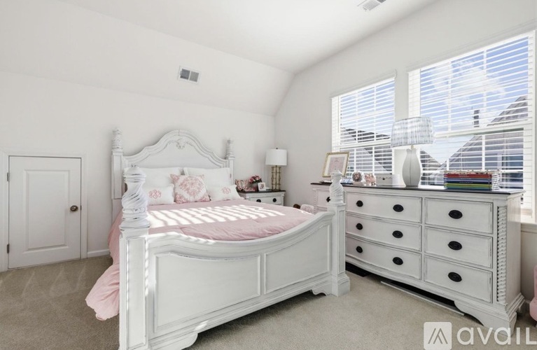 A white bedroom with a large bed and a dresser.