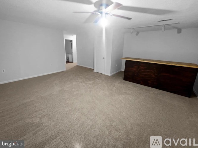 A spacious room with a ceiling fan and carpeted floor.
