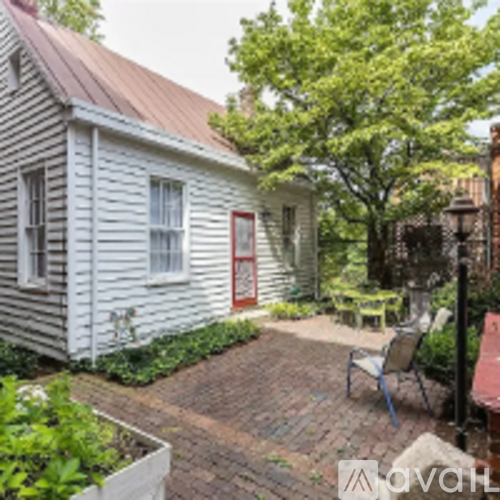 A small white house with a red door and a red brick walkway.