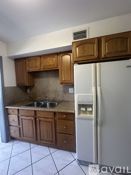 A kitchen with brown cabinets and a white fridge.