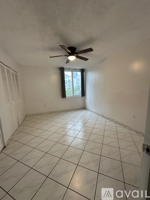 A room with a ceiling fan and a window with a view of a building outside.