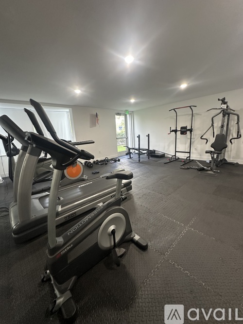 A gym with a row of stationary bikes and a weight machine.