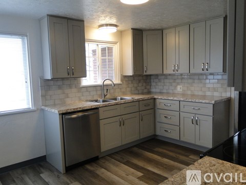 A kitchen with wooden floors and a sink under a window.