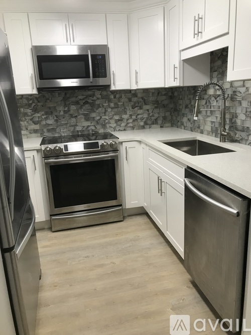 A kitchen with white cabinets and a stainless steel refrigerator.