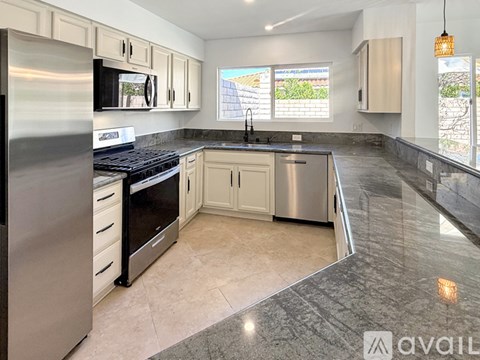 A kitchen with a black counter top and stainless steel appliances.