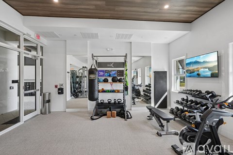 A gym with a variety of equipment including a treadmill, weights, and a television.
