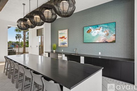 A modern kitchen with a long black table and chairs.