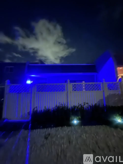 A house with blue lights and a white fence.