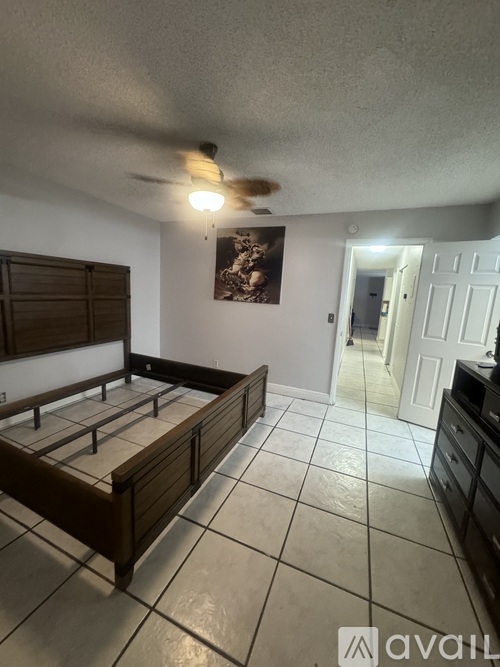 A bedroom with a bed, dresser, and a ceiling fan.