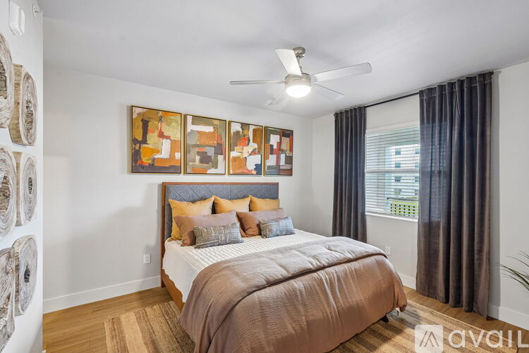 A bedroom with a bed, pillows, a ceiling fan, and a wall with framed artwork.