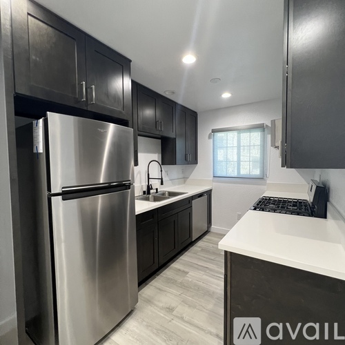 A modern kitchen with a stainless steel refrigerator and dark cabinets.