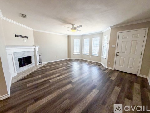 A spacious room with a fireplace and wooden flooring.