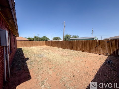 A backyard with a wooden fence and a grassy area.
